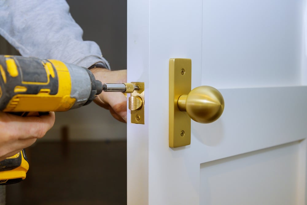 Closeup of Locksmith Using Electric Screwdriver to Install Door Lock